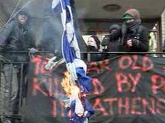 Анархисты сжигают греческий флаг в Лондоне. Кадр те
		<!--
