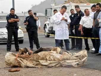 Мексиканские криминалисты осматривают тело убитого. Фото ©AFP, архив